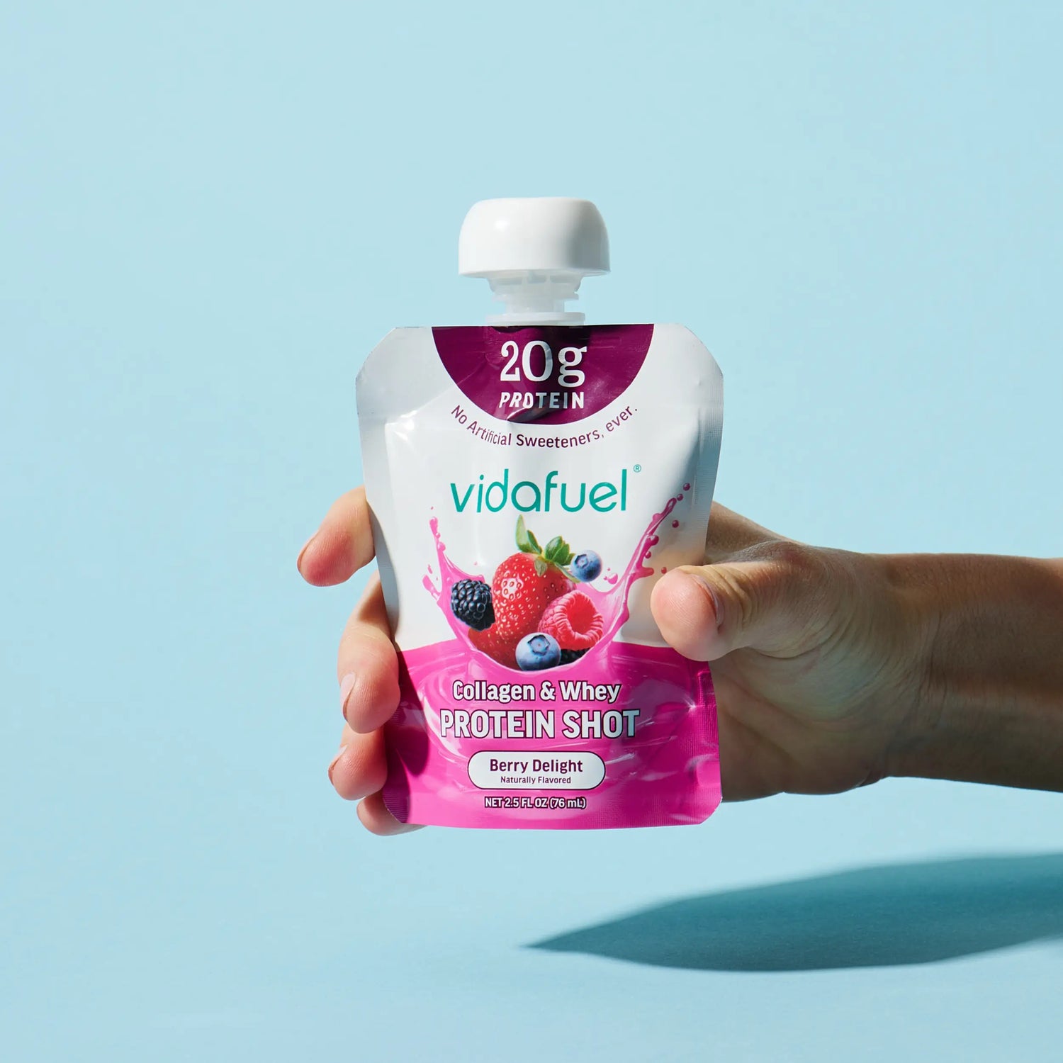 Hand holding a Vidafuel protein shot pouch against a light blue background